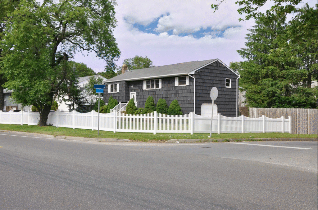 a white concave picket fence surrounding the front yard of a north eastern american home