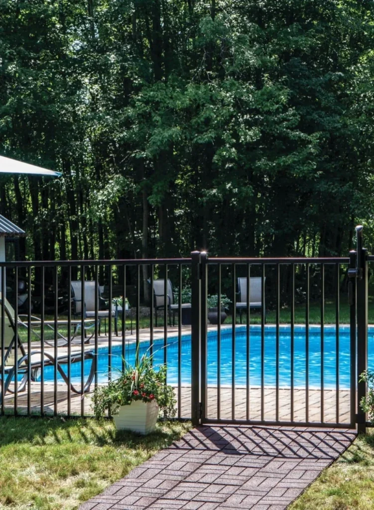a black aluminum fence surrounding a pool area with a gate featuring a safety latch