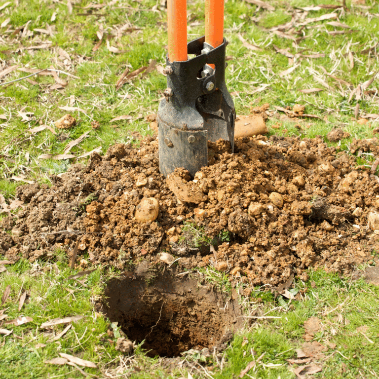 a hole being dug by a set of post hole diggers, in a residential yard prior to installing a residential fence