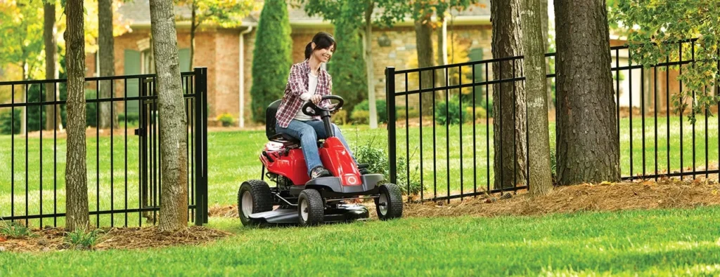 a woman driving a lawnmower through a residential aluminum gate