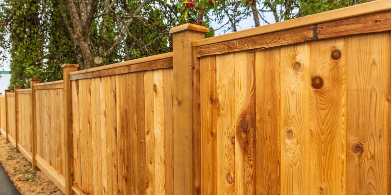 a stained custom wood privacy fence with cap board and post caps