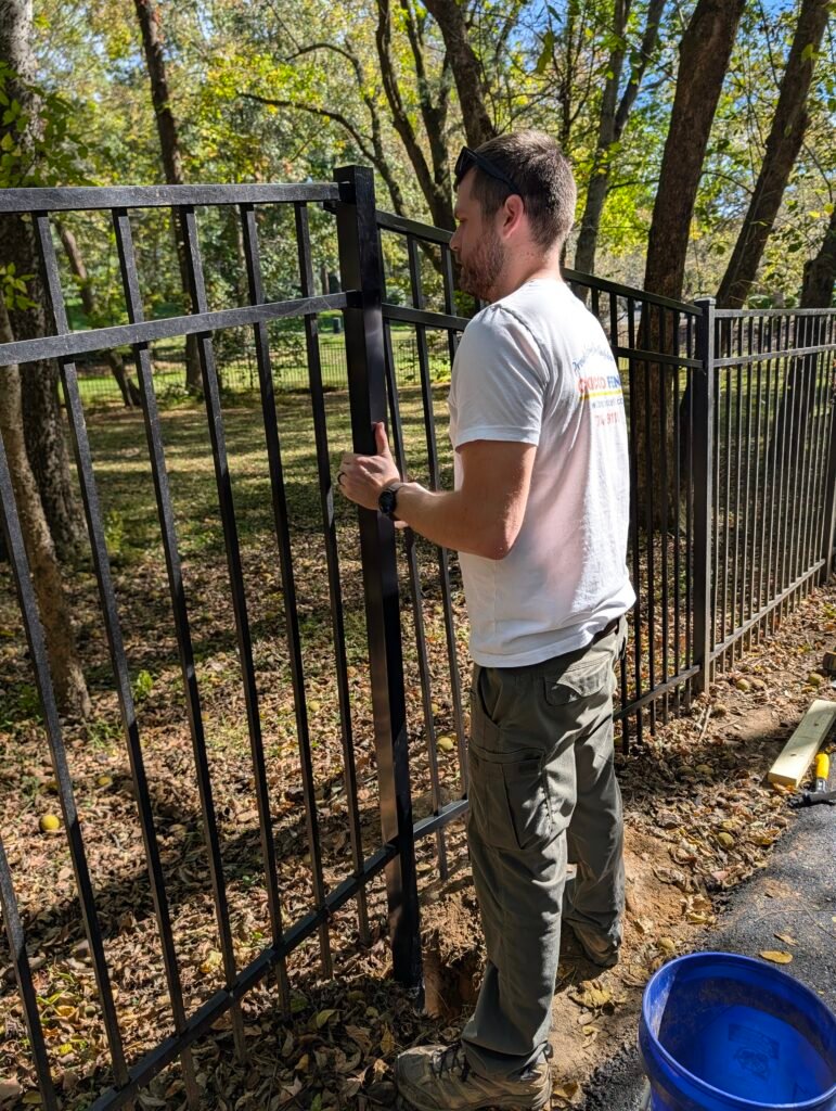 Jake from Concord Fence holding two sections of an aluminum fence while repairing it