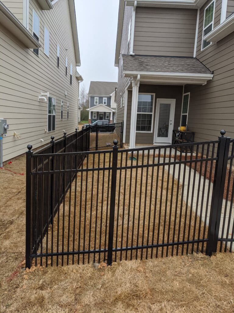 A black aluminum fence with double picket spacing for smaller breed dogs