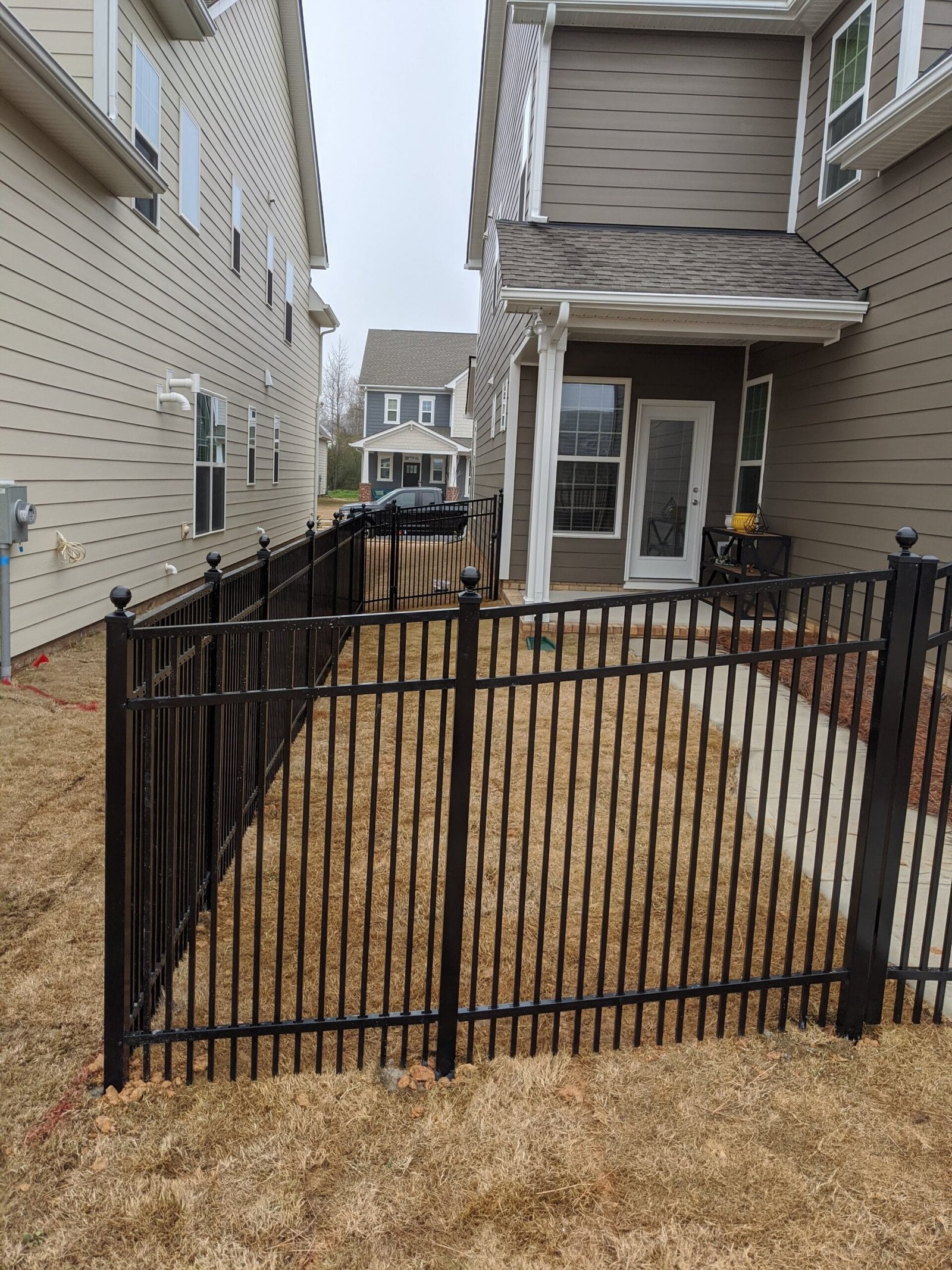 A black aluminum fence with double picket spacing for smaller breed dogs